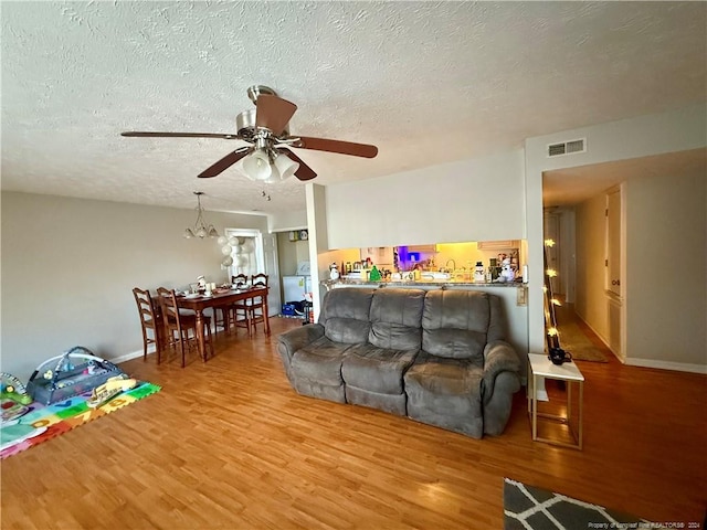 living room with hardwood / wood-style flooring, ceiling fan, and a textured ceiling