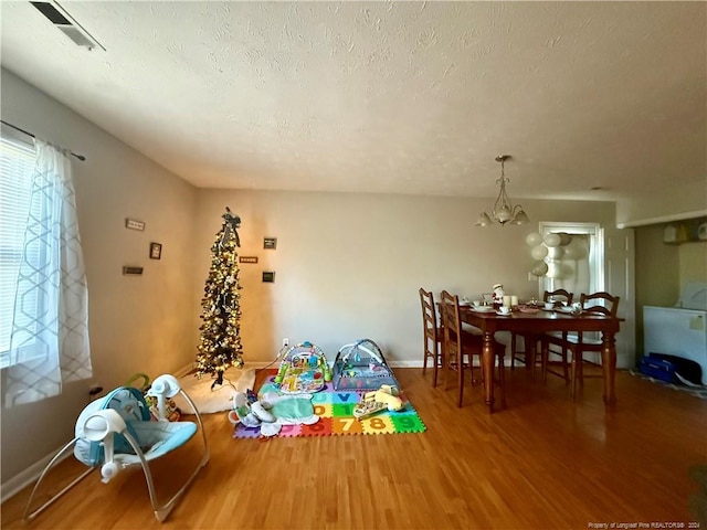 dining space with a textured ceiling, hardwood / wood-style flooring, and a notable chandelier