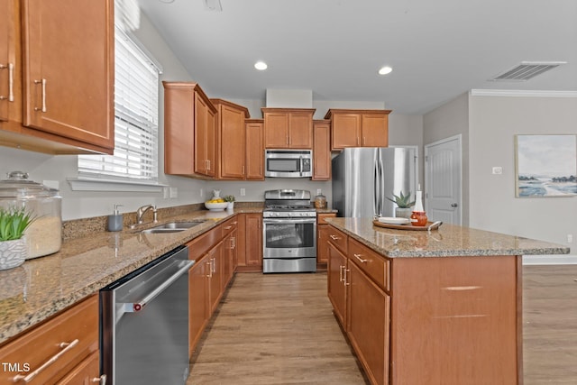 kitchen featuring a kitchen island, appliances with stainless steel finishes, sink, and light hardwood / wood-style flooring