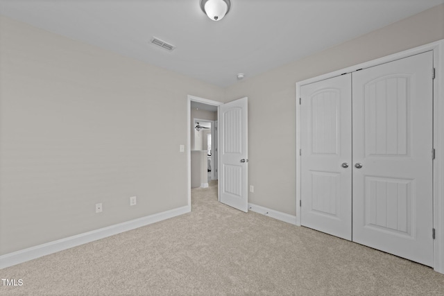 unfurnished bedroom featuring light colored carpet and a closet