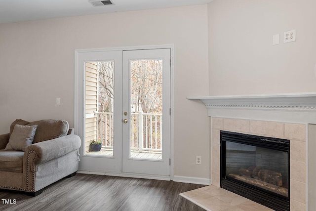 doorway featuring hardwood / wood-style floors, a wealth of natural light, and a tiled fireplace