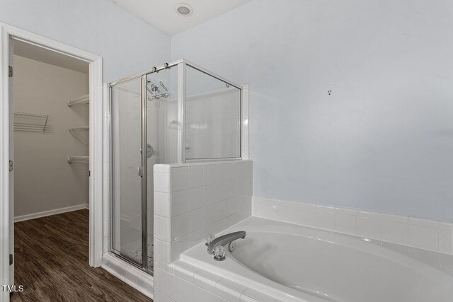524 Glenolden Ct, Cary, NC 27513 - bathroom with a bath, a spacious closet, a stall shower, and wood finished floors