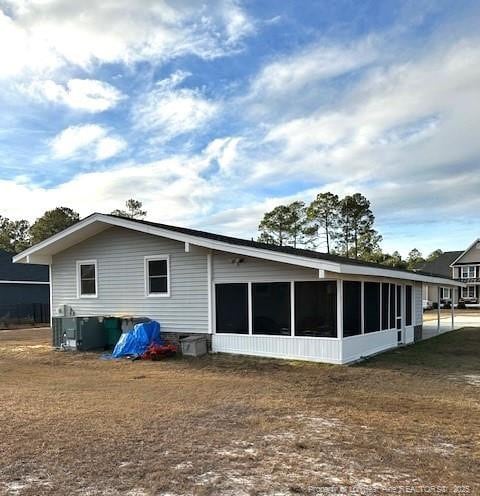 rear view of house with central AC unit and a sunroom