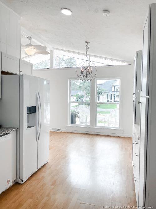 kitchen with pendant lighting, lofted ceiling, white appliances, light hardwood / wood-style floors, and white cabinetry