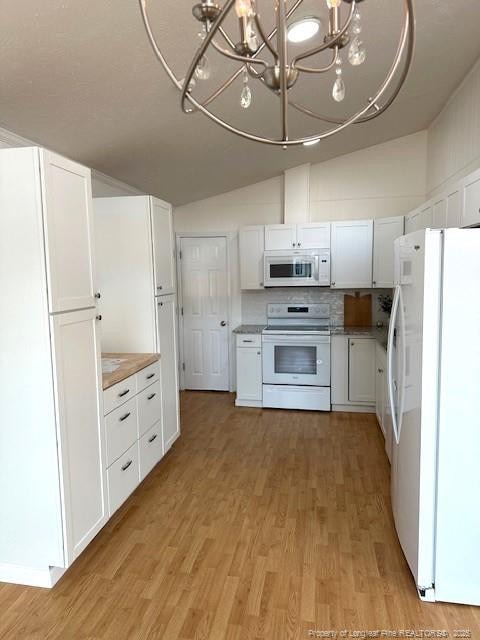 kitchen featuring white appliances, vaulted ceiling, light hardwood / wood-style floors, white cabinetry, and a chandelier