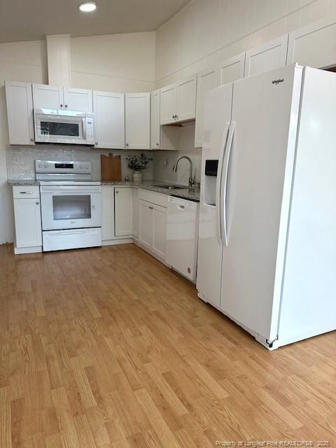 kitchen with decorative backsplash, white appliances, white cabinetry, and sink