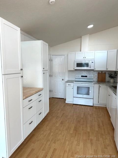 kitchen featuring decorative backsplash, white appliances, white cabinetry, and vaulted ceiling