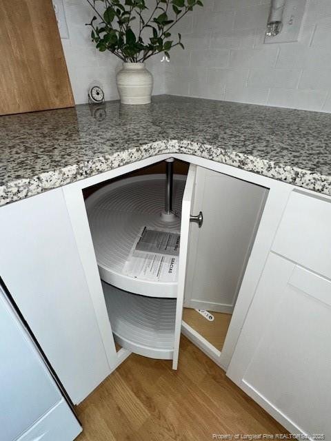 details featuring white cabinets, decorative backsplash, light hardwood / wood-style floors, and light stone countertops