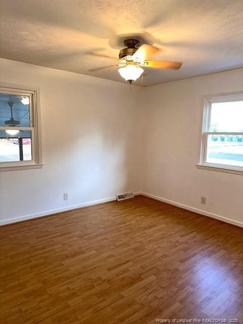 empty room featuring a textured ceiling, ceiling fan, and dark wood-type flooring