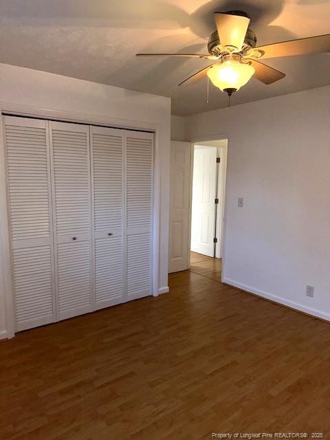 unfurnished bedroom featuring a closet, ceiling fan, and dark wood-type flooring