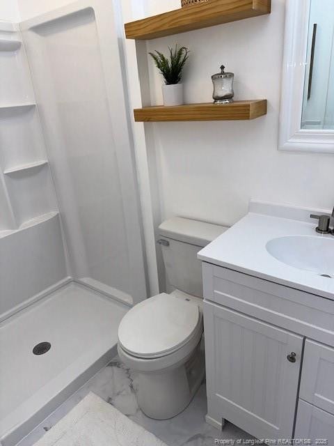 bathroom with a shower, vanity, and toilet