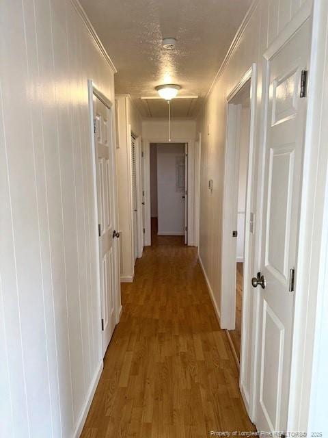 hall with hardwood / wood-style flooring, a textured ceiling, and ornamental molding