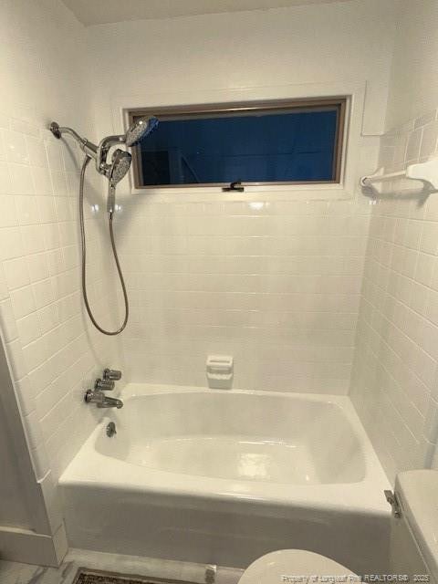 bathroom featuring toilet and tiled shower / bath