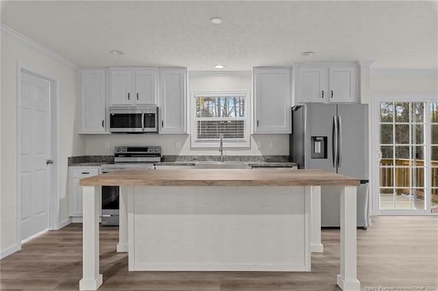 kitchen with wooden counters, white cabinets, sink, appliances with stainless steel finishes, and light hardwood / wood-style floors