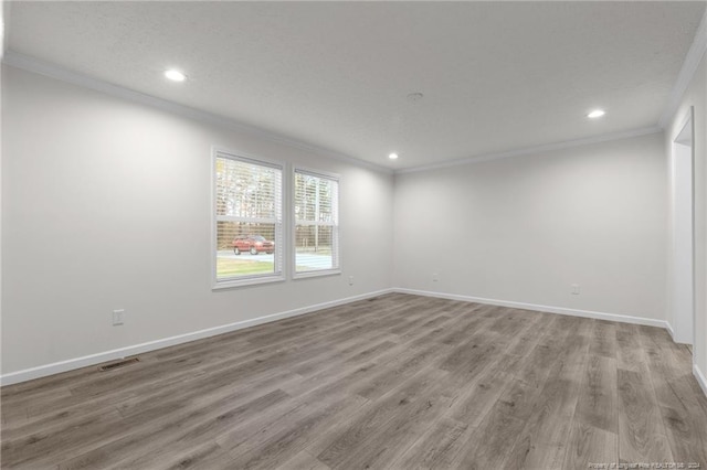 spare room with a textured ceiling, light wood-type flooring, and ornamental molding