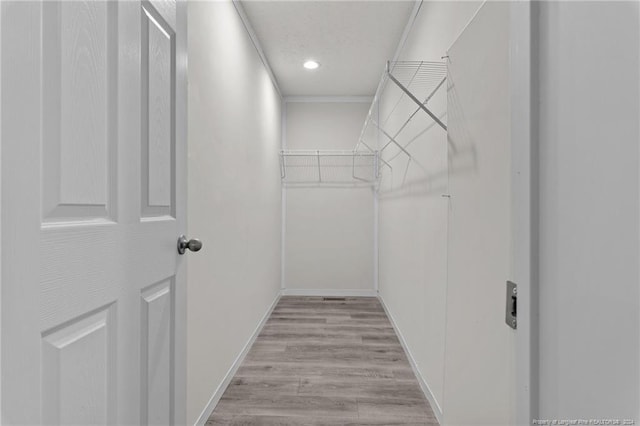 walk in closet with light hardwood / wood-style floors