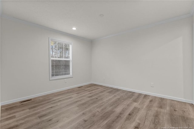 spare room featuring ornamental molding and light wood-type flooring