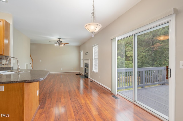 interior space with tasteful backsplash, a fireplace with flush hearth, a sink, wood finished floors, and baseboards