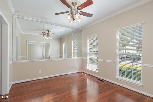 unfurnished room with visible vents, crown molding, baseboards, and wood finished floors