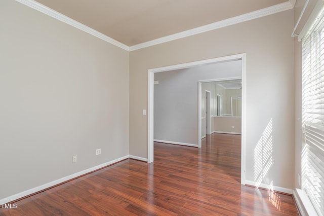 empty room featuring crown molding, baseboards, and wood finished floors