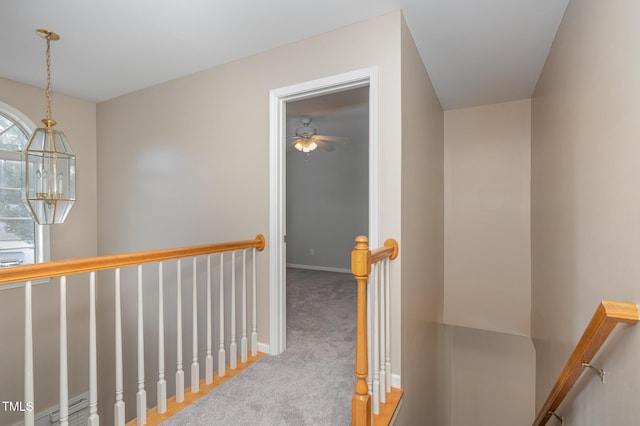 hall with carpet floors, an upstairs landing, and baseboards