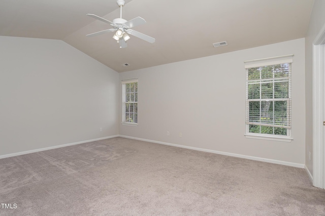 unfurnished room featuring lofted ceiling, baseboards, visible vents, and light colored carpet