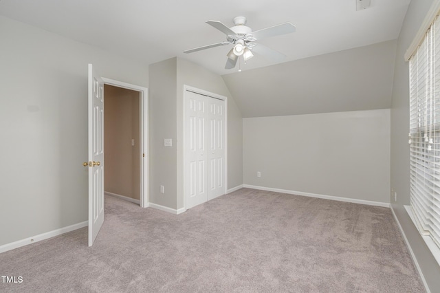 unfurnished bedroom featuring lofted ceiling, a closet, a ceiling fan, carpet flooring, and baseboards