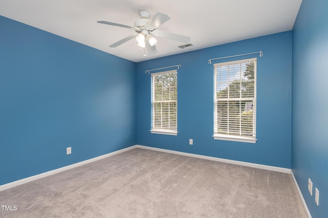 carpeted spare room with ceiling fan, visible vents, and baseboards