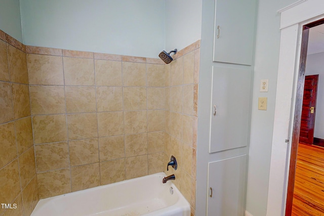 bathroom with tiled shower / bath combo and hardwood / wood-style flooring