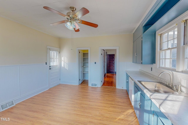 kitchen featuring ceiling fan, ornamental molding, sink, and light hardwood / wood-style flooring