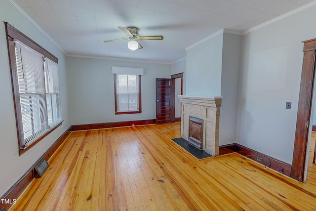 unfurnished living room with ceiling fan, a fireplace, ornamental molding, and light wood-type flooring