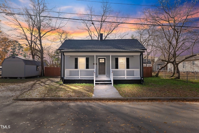 bungalow-style house featuring a porch and a storage shed