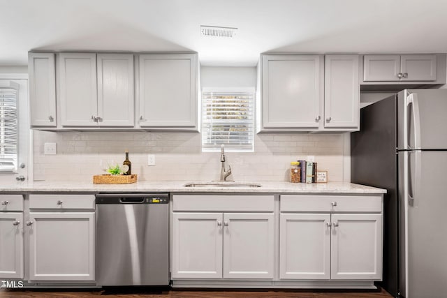 kitchen with light stone countertops, stainless steel appliances, backsplash, and sink