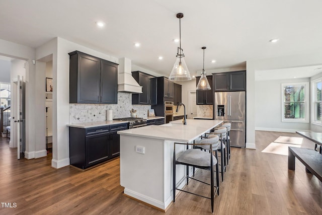 kitchen with premium range hood, hanging light fixtures, a kitchen breakfast bar, a kitchen island with sink, and high quality appliances