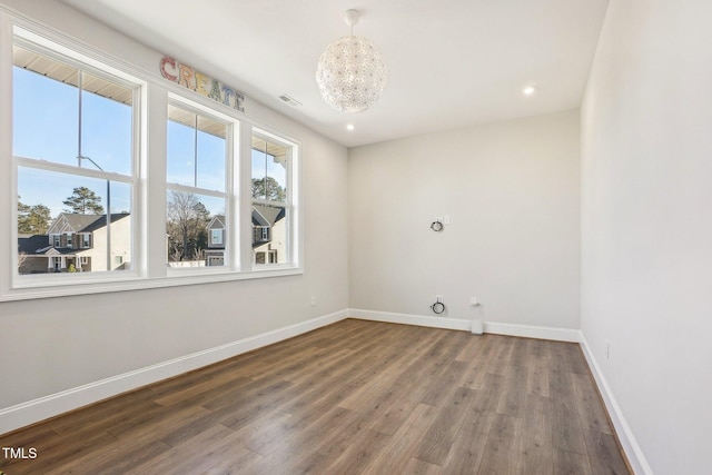 empty room with dark wood-type flooring and a notable chandelier