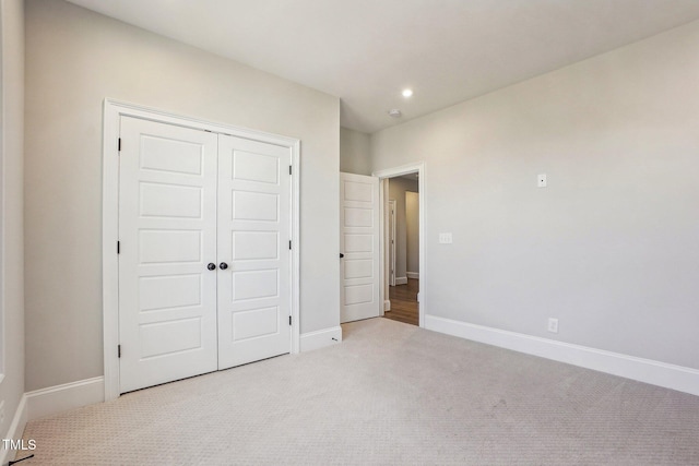 unfurnished bedroom featuring a closet and light colored carpet