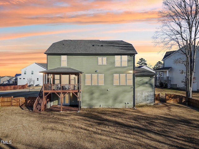 back house at dusk featuring a deck and a yard