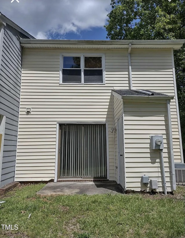 back of property with central AC unit and a yard