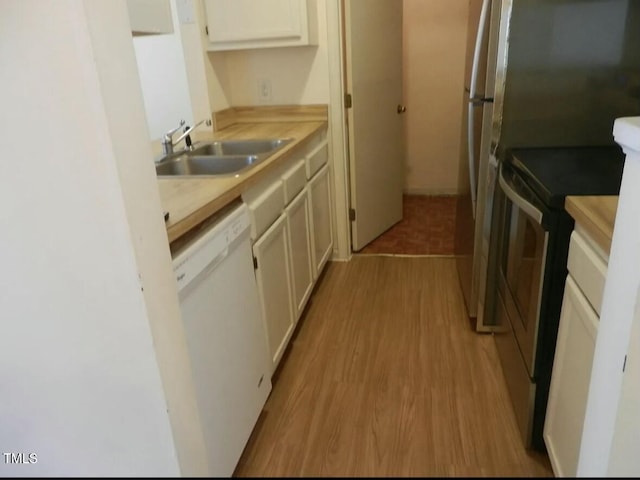 kitchen featuring stainless steel range with electric cooktop, white dishwasher, sink, light hardwood / wood-style flooring, and white cabinetry