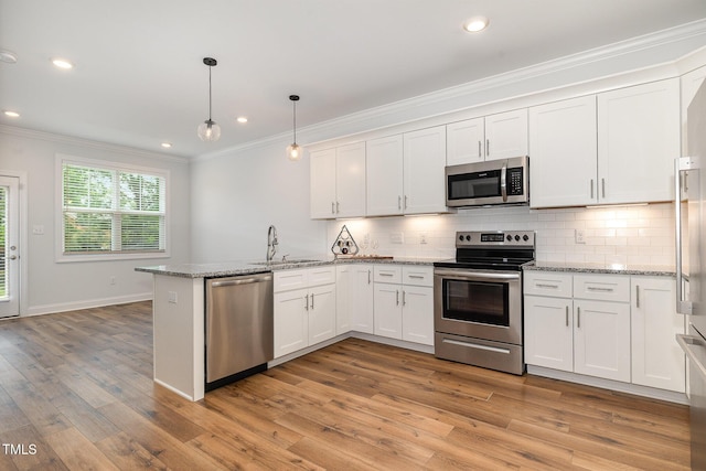 kitchen featuring white cabinets, pendant lighting, kitchen peninsula, and appliances with stainless steel finishes