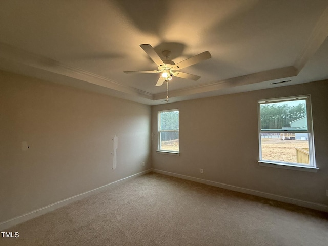 carpeted empty room featuring a tray ceiling and ceiling fan