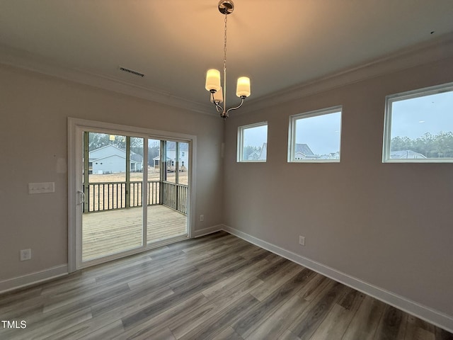 spare room featuring an inviting chandelier, hardwood / wood-style flooring, and ornamental molding