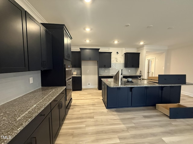 kitchen featuring a breakfast bar, backsplash, light wood-type flooring, and dark stone counters