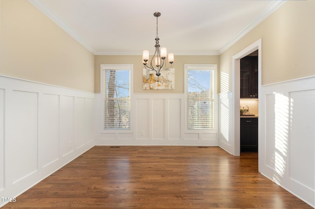 unfurnished dining area with ornamental molding, dark wood-type flooring, and a notable chandelier