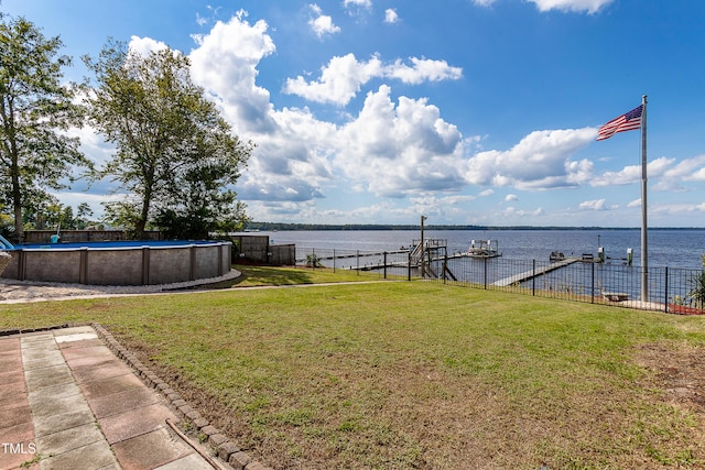 view of yard with a boat dock, a water view, and a fenced in pool