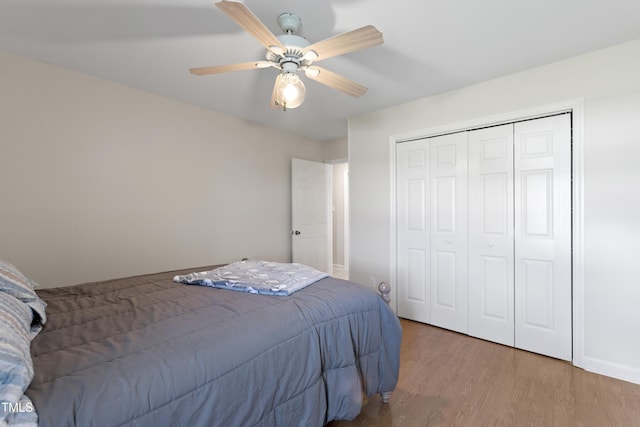 bedroom with ceiling fan, wood-type flooring, and a closet