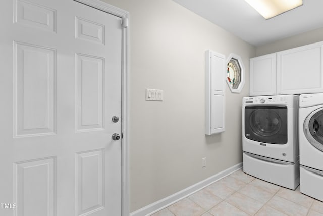 laundry room with washer and clothes dryer, cabinets, and light tile patterned floors