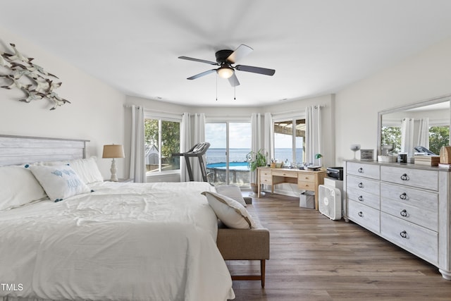 bedroom with access to outside, a water view, multiple windows, and dark wood-type flooring