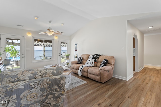 living room with light wood-type flooring, a water view, vaulted ceiling, and ceiling fan