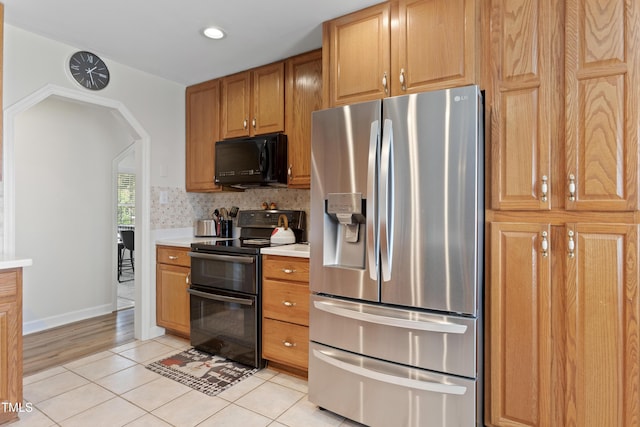 kitchen featuring tasteful backsplash, light tile patterned flooring, and black appliances